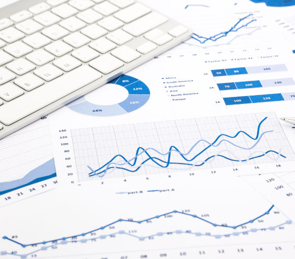 closeup blue graph and chart reports with white keyboard and pen on office table, financial and business concept
